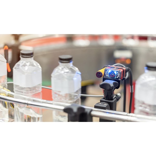 En sensor med et digitalt display kontrollerer flasker på et rullebånd.